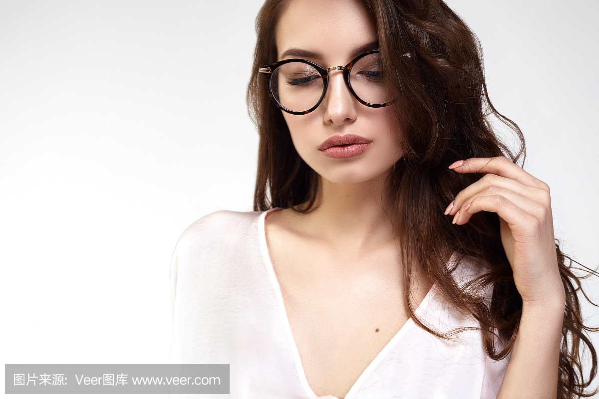 女性的眼睛穿。迷人的黑發女孩與自然臉化妝在透明眼鏡框架。美麗的女人的臉。美麗性感的年輕女性肖像與完美的化妝,柔軟新鮮健康的皮膚和厚厚的黑色長睫毛。灰色上的迷人女孩
